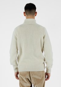 Crème-kleurige gebreide trui met een hoge kraag en geribbelde manchetten en zoom. Gekocht met lichtbruine corduroy broek.