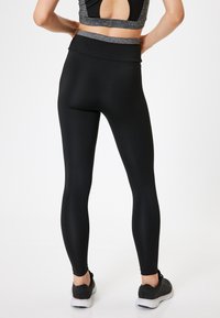 Leggings negros con una cinturilla alta y una tela suave y elástica. El diseño es ajustado, con un corte que se estrecha en los tobillos.