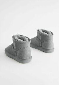 Graue Wildleder-Stiefeletten mit einem weichen, flauschigen Innenfutter, runder Zehenpartie und flacher Sohle, die sichtbare Nähte und ein schlichtes Design aufweisen.