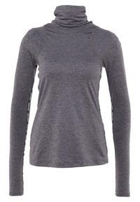 Haut gris à col roulé manches longues avec une coupe ajustée, une texture douce, et des détails latéraux contrastants avec un marquage noir et blanc.