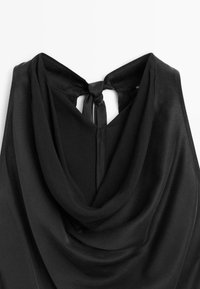 Top nero con colletto a cappuccio realizzato in un tessuto morbido e liscio, con dettaglio di apertura a chiave sul retro e chiusura legata sul collo. Design leggero e drappeggiato.