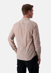 Camicia a maniche lunghe color rosa chiaro con motivo floreale. Realizzata in cotone, presenta un colletto a punta e spacco ai lati dell'orlo.