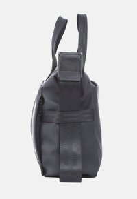 Schwarze wasserdichte Tasche mit runder Form. Verfügt über einen flachen Boden, robuste seitliche Träger und einen Reißverschluss für den Zugang zum Hauptfach.