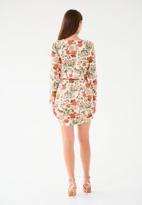 Kwiecista sukienka z długimi rękawami, z kremowym tłem, pomarańczowymi i różowymi kwiatami, z marszczeniami i dopasowanym krojem.
