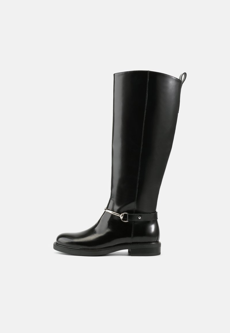 Botas de couro pretas brilhantes até ao joelho com um design simples, apresentando uma corrente e fivela de metal prateado perto do tornozelo. Sola de borracha plana.