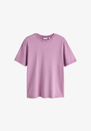 Krótki rękaw, jasnofioletowa bawełniana koszulka z okrągłym dekoltem i małym żółtym haftowanym logo na lewej piersi.