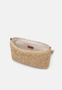 Borsa in paglia intrecciata di colore naturale con superficie testurizzata, dotata di un interno in tessuto beige e una piccola etichetta in pelle.