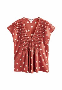 Blouse couleur rouille avec des pois blancs, un décolleté en V, des manches courtes et des plis verticaux à l'avant pour texture et fluidité.