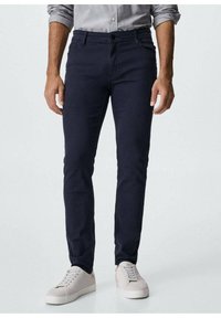 Námořnické chinos kalhoty vyrobené z elastického bavlněného materiálu, slim-fit střih, pět kapes, s zipovým zapínáním a knoflíkovým uzávěrem, v kombinaci s lehkými teniskami.