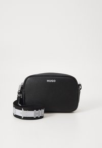 Svart lær crossbody-veske med rektangulær form, utstyrt med et sølvlogo og en kontrastfarget mønstrete stoffreim.