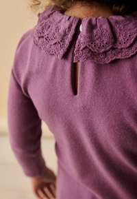 Lila Pullover mit einem gerüschten Spitzenkragen, der ein kleines Schlüssellochdetail auf der Rückseite sowie lange Ärmel und ein strukturierter Stoff hat.