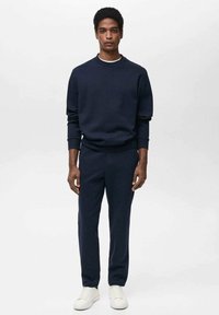 Mornarska majica in usklajene zožene hlače iz mehkega materiala. Rebrasti manšeti in pas, v kombinaciji z belimi teniskami.