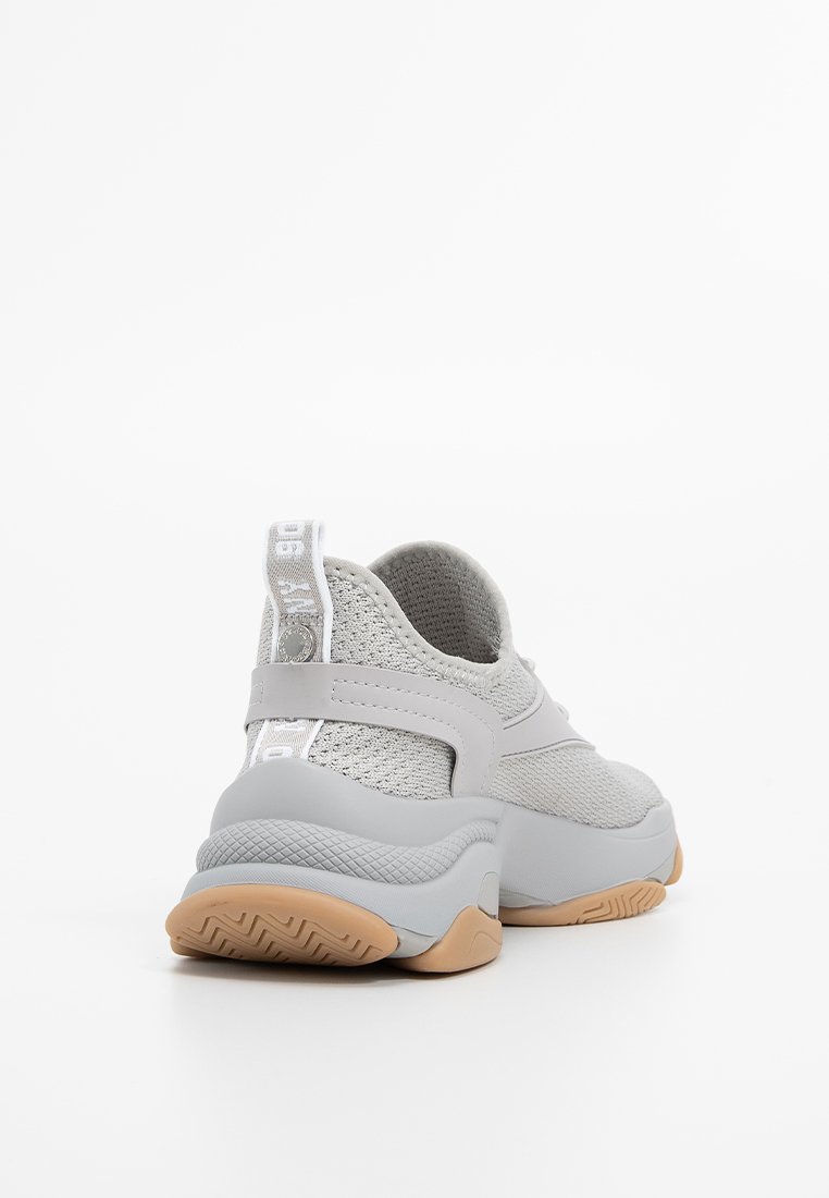Zapatillas deportivas gris claro con parte superior de malla transpirable, suela de goma y contrafuerte acolchado; presentan un diseño texturizado y una correa ajustable.