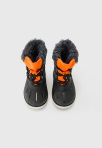 Schwarze und orange Winterstiefel mit grauem, flauschigem Futter, schwarzen Schnürsenkeln und weißen Sohlen, von oben auf einem weißen Hintergrund betrachtet.