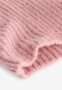 Gestrickter pinkfarbener Wollstoff mit gerippter Textur, der weiche, flauschige Fasern und einen glatten Rand aufweist.