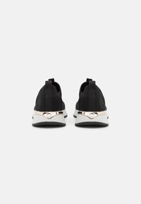 Black mesh sneakers with a sleek design, featuring a metallic silver accent on the heel and a textured black rubber sole.
