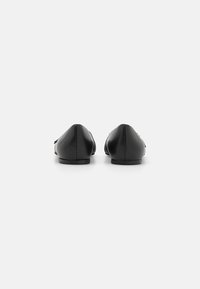 Bailarinas de piel negra con punta afilada y diseño minimalista. Textura suave con sutiles acentos de costura. Tacón bajo y plano.