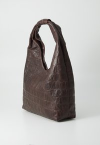 Sac en cuir marron avec un design texturé en relief crocodile. Forme unique avec une seule poignée tordue et une base triangulaire.