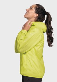 Limegrüne, leichte Jacke mit Kapuze, mit glatter Textur, verstellbaren Kordeln und minimaler Markenkennzeichnung am Ärmel.