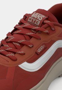 Røde Vans-sneakers med en teksturert overflate, hvit sideprofil og mønstrede røde snører. Har en polstret krage og logo-merke på tungen.