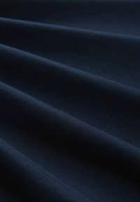 Tessuto blu navy scuro con una texture liscia, caratterizzato da pieghe ondulate che creano profondità e dimensione. Nessun motivo o accento visibile.