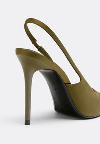Chaussure slingback à talon haut vert olive avec un talon stiletto fin et un détail de bride élastique sur fond blanc uni.