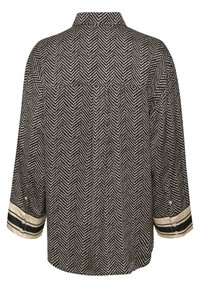 Chemise à motif en chevrons noir et blanc avec un col mandarin, des manches retroussées présentant des rayures crème et noires, et une coupe ample.