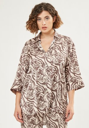 Camisa de botones de patrón marrón y crema con un corte holgado, mangas anchas y un bolsillo delantero. Tela suave con una textura sedosa.