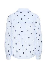 Blusa azzurro chiaro con maniche lunghe, decorata con piccoli fiori blu scuro e polsini con bottoni, vista da dietro.