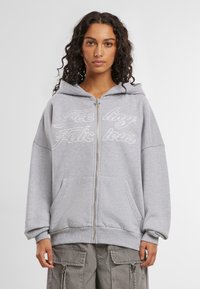 Grauer Reißverschluss-Hoodie mit Kapuze und Kordelzug, Fronttaschen und dekorativer weißer Schrift. Verfügt über eine lockere Passform sowie gerippte Bündchen und Saum.