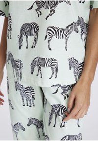 Mintgrünes Baumwoll-Loungewear-Set mit einem allover schwarzen Zebra-Print. Das Oberteil hat kurze Ärmel und die Hose ist bequem geschnitten.