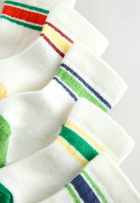 Päť bielych členkových ponožiek s farebnými pruhmi na lemoch a pätách v oranžovej, zelenej, žltej, modrej a hnedej farbe, usporiadaných prekrývajúcich sa na svetlom pozadí.