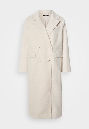 Manteau en laine blanc croisé avec revers, deux poches avant et tissu texturé. Dispose de six boutons et de manches courtes.