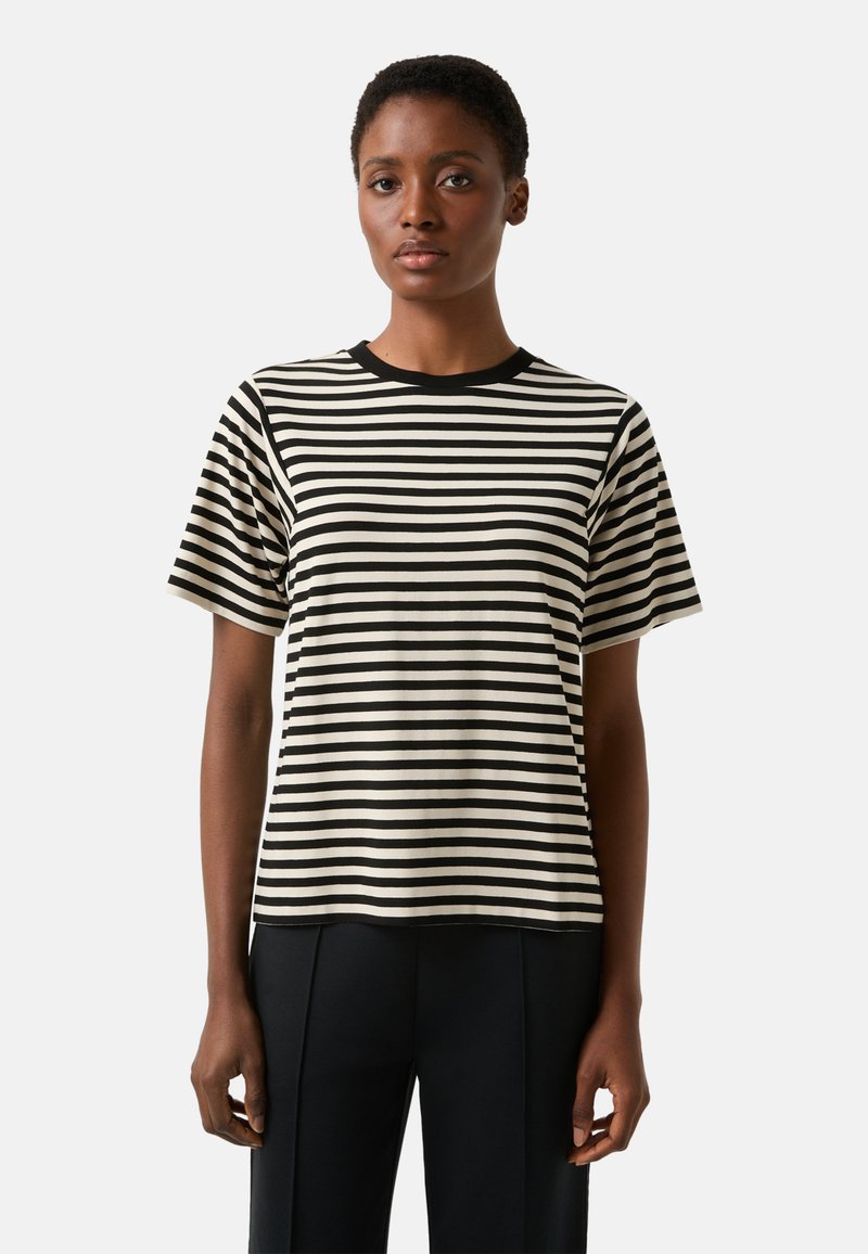 Koszulka w paski z czarnymi i kremowymi poziomymi paskami, krótkimi rękawami i okrągłym dekoltem, zestawiona z czarnymi, dopasowanymi spodniami.