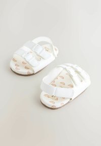 White toddler sandals with two adjustable straps, rubber soles, and patterned insoles featuring pink rainbows on a light background.