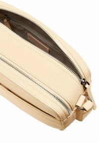 Clutch in pelle beige con finitura testurizzata. Presenta due cerniere argentee, una base piatta e hardware laterale per il fissaggio. Interno foderato.