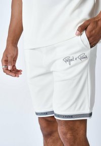 Shorts deportivos blancos con relieve y con marca gris en el dobladillo. Cuentan con un bolsillo lateral y una cintura elástica para mayor comodidad.