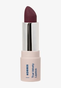 Rouge à lèvres Korres True Velvety de couleur prune profonde dans un tube rose clair avec un intérieur métallique argenté.