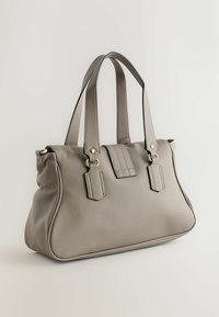 Harmaa nahkainen käsilaukku, jossa on kaksi lyhyttä kahvaa, koristeltu ommelluilla yksityiskohdilla, kultaisilla metalliosilla ja jämäkällä rakenteella. Pinnan tekstuuri on muhkuinen ja reunat sileät.