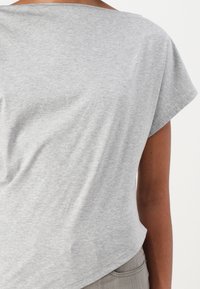 Top grigio a maniche corte realizzato in un morbido misto cotone; presenta una scollatura ampia e una vestibilità comoda, con una texture liscia e un design minimale.