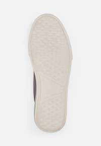 Schuhsohle mit einer strukturierten, beigen GummOberfläche und einem dunkelbraunen oberen Bereich. Enthält ein dezentes Rautenmuster für besseren Halt.