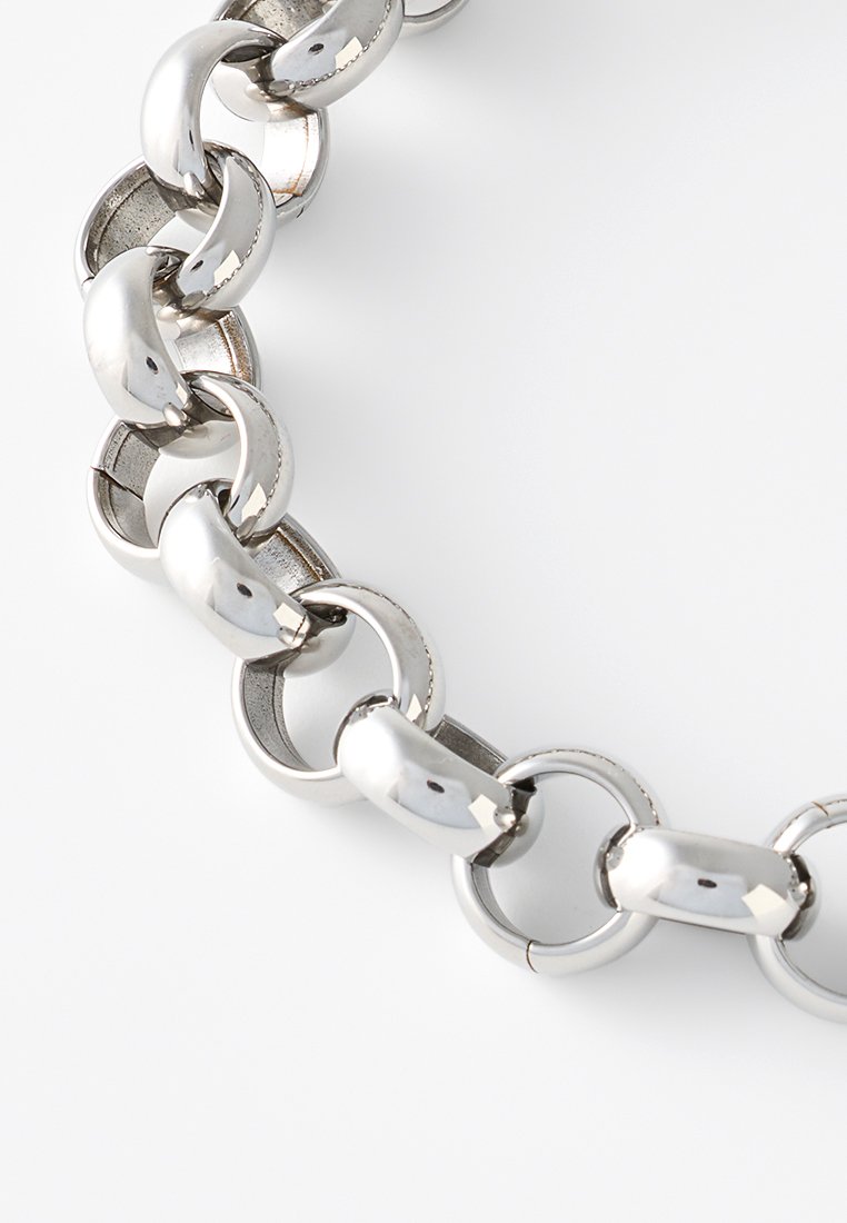 Collana in metallo argentato con maglie ovali, finitura lucida e collegamenti senza soluzione di continuità. Superficie liscia con riflessi.