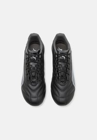 Scarpe da calcio sintetiche nere con una texture liscia, punta arrotondata, chiusura con lacci e un accento grigio di lato.