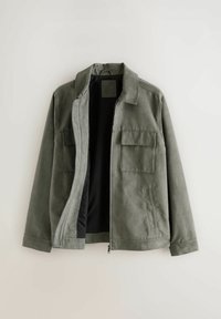 Veste vert olive avec une fermeture éclair, deux poches avant, un col et une texture douce. Conçue avec une doublure intérieure noire contrastante.