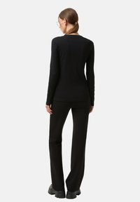 Černá dlouhý rukáv košile a odpovídající kalhoty z měkké látky, přiléhavý střih, s minimálním zdobením, s otevřeným výstřihem a rozšířenými nohavicemi.