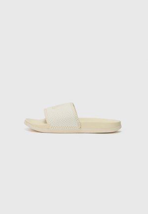 Light beige slide sandals with a textured upper featuring small perforations, a flat sole, and smooth edges for comfort.