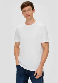 Weißes Baumwoll-T-Shirt mit Rundhalsausschnitt und kurzen Ärmeln, kombiniert mit blauen Jeans. Schlichte, glatte Textur und reguläre Passform.