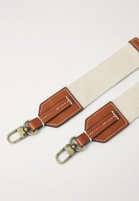 Leinenriemen mit braunen Lederakzenten, Messingbeschlägen und weißer Naht; flaches, rechteckiges Design; zwei Metallclips an jedem Ende.