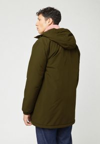 Olijfgroene pufferjack met een capuchon, voorzien van een roze fleece-gevoerde kraag en elastische manchetten. Het materiaal lijkt glad met een matte afwerking.