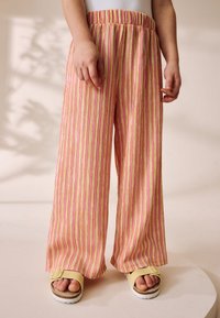 Pantalon à jambes larges rayé rose et jaune avec une ceinture élastique, fabriqué dans un tissu léger, offrant une coupe décontractée.
